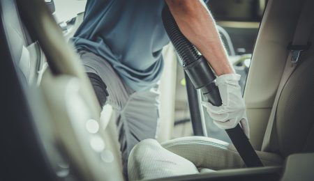 Vehicle Cleaning Worker Vacuuming Front Passenger Leather Seat. Car Interior Care and Maintenance Activities. Professional Auto Detailing Services Theme. Horizontal Photo.